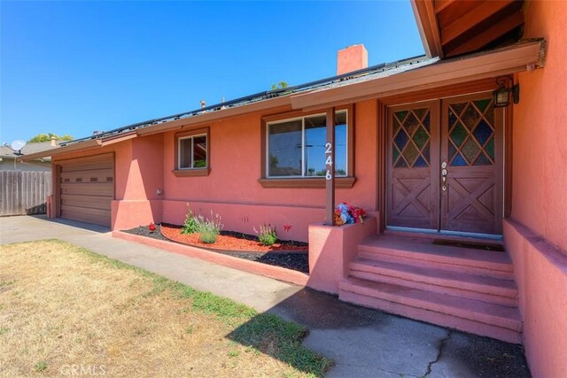 246 E Shasta St, Orland, CA 95963 - property entrance featuring a chimney, stucco siding, and concrete driveway