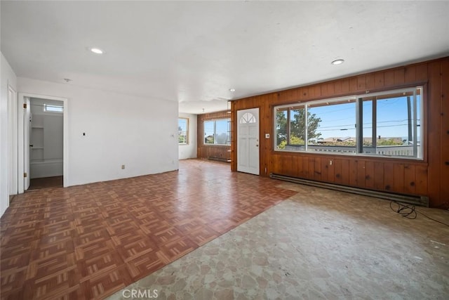 1799 Saint Thomas Ave, Cambria, CA 93428 - unfurnished living room with a baseboard radiator, wood walls, and recessed lighting
