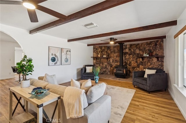 27363 Azurite Rd, Barstow, CA 92311 - living area with a ceiling fan, a wood stove, arched walkways, beam ceiling, and light wood-style flooring