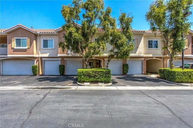 93 Kansas St Unit 205, Redlands, CA 92373 - townhome / multi-family property featuring a garage, stucco siding, a tiled roof, and driveway