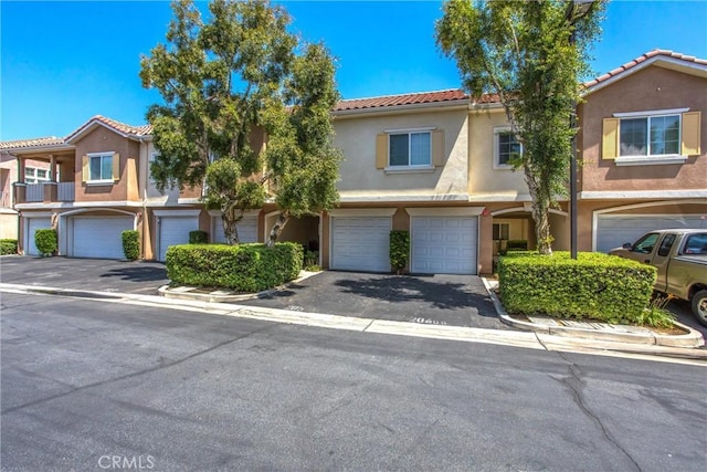 93 Kansas St Unit 205, Redlands, CA 92373 - view of property with a garage, stucco siding, a tiled roof, and driveway