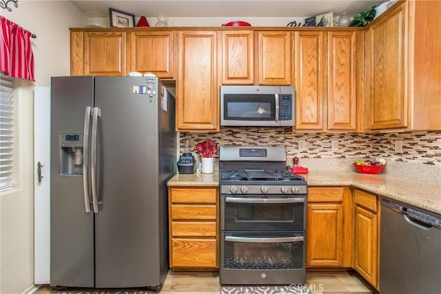93 Kansas St Unit 205, Redlands, CA 92373 - kitchen featuring appliances with stainless steel finishes, tasteful backsplash, and brown cabinets