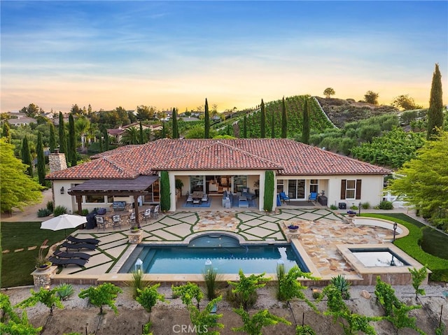 33260 Susan Grace Ct, Temecula, CA 92592 - pool at dusk with exterior bar, a patio, a pool with connected hot tub, an outdoor living space, and outdoor dining space