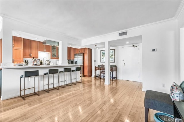 1203 N Sweetzer Ave Unit 215, West Hollywood, CA 90069 - kitchen featuring a breakfast bar, stainless steel fridge with ice dispenser, brown cabinets, light countertops, and light wood-type flooring