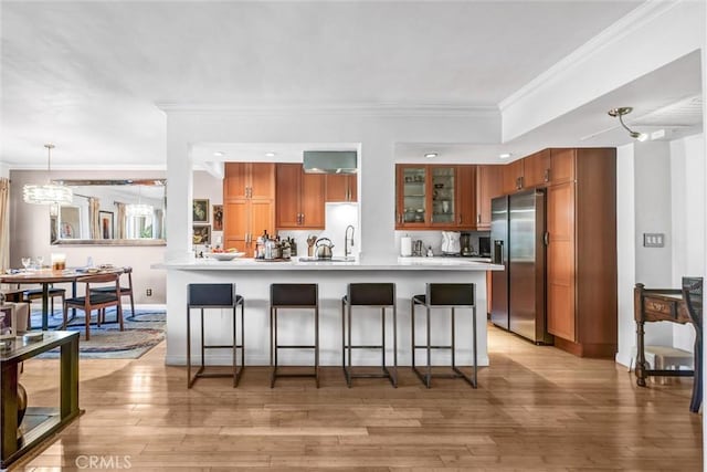 1203 N Sweetzer Ave Unit 215, West Hollywood, CA 90069 - kitchen featuring stainless steel fridge with ice dispenser, a breakfast bar, light countertops, crown molding, and brown cabinetry