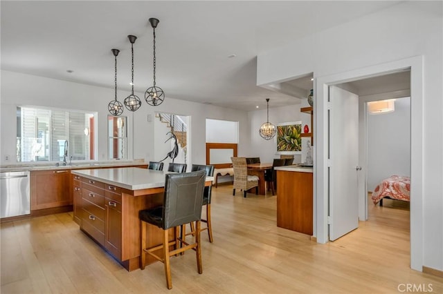 426 Nyes Pl, Laguna Beach, CA 92651 - kitchen featuring brown cabinetry, stainless steel dishwasher, a breakfast bar, light wood-type flooring, and light countertops