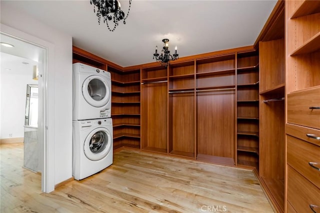 426 Nyes Pl, Laguna Beach, CA 92651 - laundry room featuring stacked washer / drying machine, a chandelier, and light wood-style floors