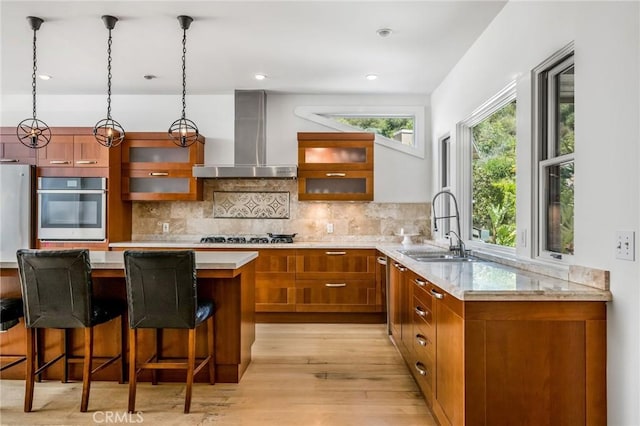 426 Nyes Pl, Laguna Beach, CA 92651 - kitchen with oven, wall chimney range hood, brown cabinets, light wood finished floors, and tasteful backsplash