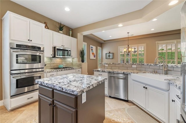 79787 Parkway Esplanade N, La Quinta, CA 92253 - kitchen featuring appliances with stainless steel finishes, tasteful backsplash, a chandelier, white cabinets, and recessed lighting