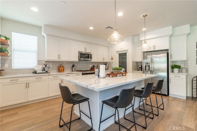1827 Montecito Ln, Redlands, CA 92374 - kitchen with appliances with stainless steel finishes, backsplash, a kitchen bar, white cabinetry, and recessed lighting