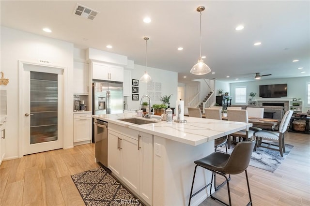 1827 Montecito Ln, Redlands, CA 92374 - kitchen with appliances with stainless steel finishes, light wood-type flooring, recessed lighting, light stone countertops, and a center island with sink