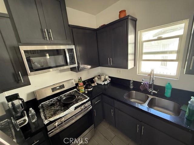 647 E 38th St, Los Angeles, CA 90011 - kitchen with appliances with stainless steel finishes, dark countertops, and tile patterned floors