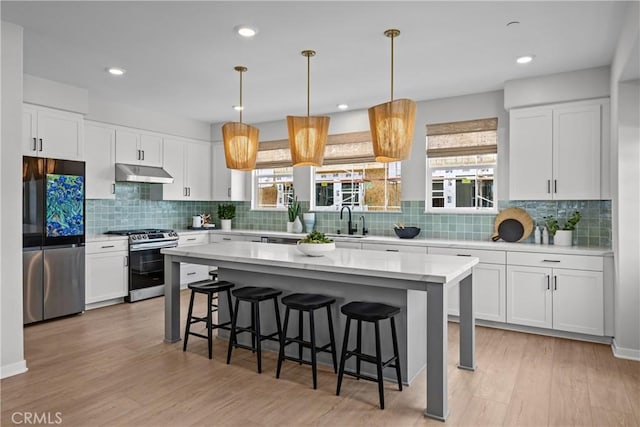 22325 Sage Ct, Torrance, CA 90502 - kitchen featuring stainless steel appliances, under cabinet range hood, a kitchen breakfast bar, tasteful backsplash, and recessed lighting