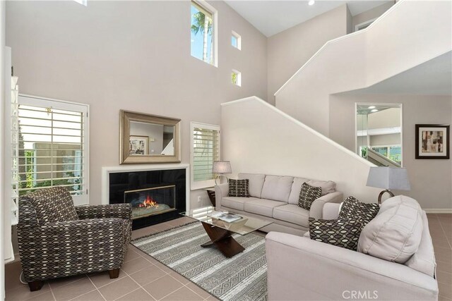 331 Parsons Lndg, Long Beach, CA 90803 - living area featuring tile patterned flooring, a towering ceiling, stairs, and a glass covered fireplace