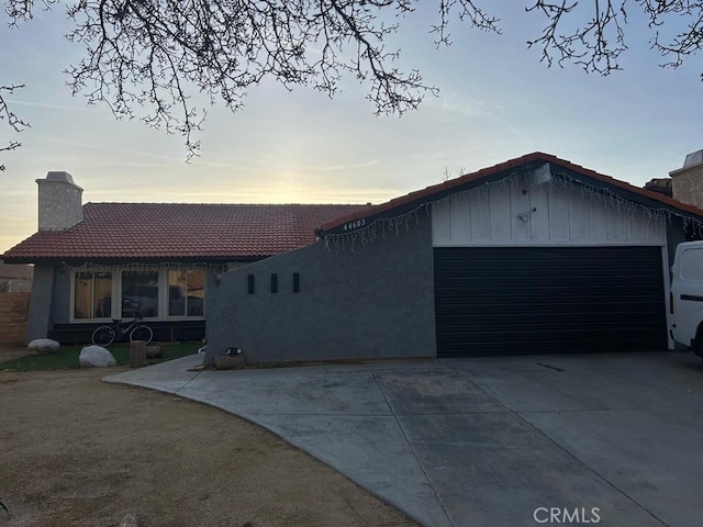 44603 13th St E, Lancaster, CA 93535 - view of front of property featuring a garage, concrete driveway, a chimney, a tiled roof, and stucco siding