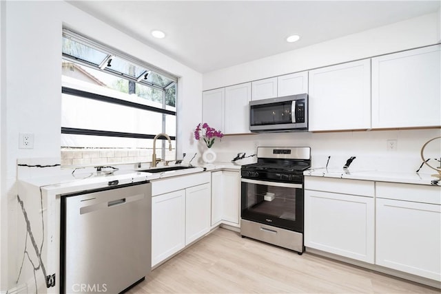 23760 Timber Bluff Ct, Moreno Valley, CA 92557 - kitchen featuring appliances with stainless steel finishes, white cabinetry, light wood-type flooring, and recessed lighting