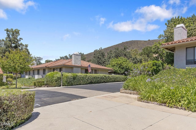 4062 Bridgewood Ln, Thousand Oaks, CA 91362 - view of front of house featuring a chimney, stucco siding, a tile roof, and a mountain view
