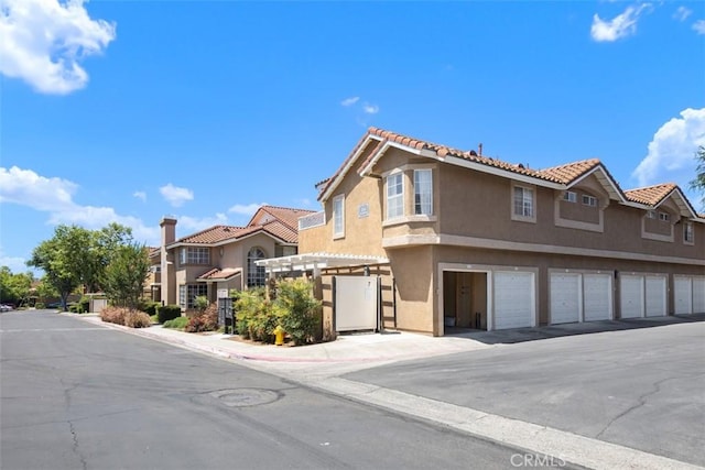 4 Via Pariente, Rancho Santa Margarita, CA 92688 - view of front facade featuring stucco siding, a residential view, community garages, and a tiled roof