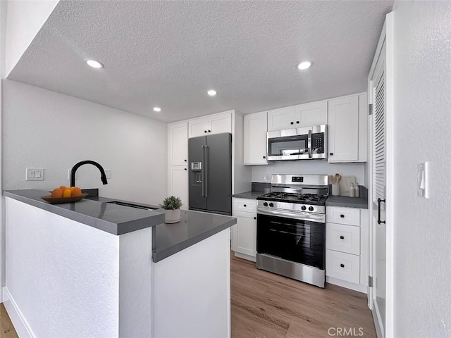 17333 Brookhurst St Unit D6, Fountain Valley, CA 92708 - kitchen with stainless steel appliances, dark countertops, light wood finished floors, white cabinetry, and a textured ceiling