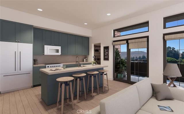 581 Higuera St Unit 306, San Luis Obispo, CA 93401 - kitchen with white microwave, paneled refrigerator, light countertops, a kitchen bar, and light wood-type flooring