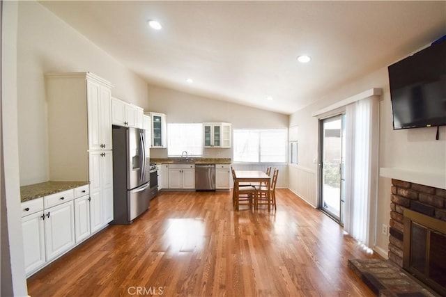 22692 Abington Pl, Moreno Valley, CA 92553 - kitchen featuring appliances with stainless steel finishes, vaulted ceiling, plenty of natural light, wood finished floors, and white cabinetry