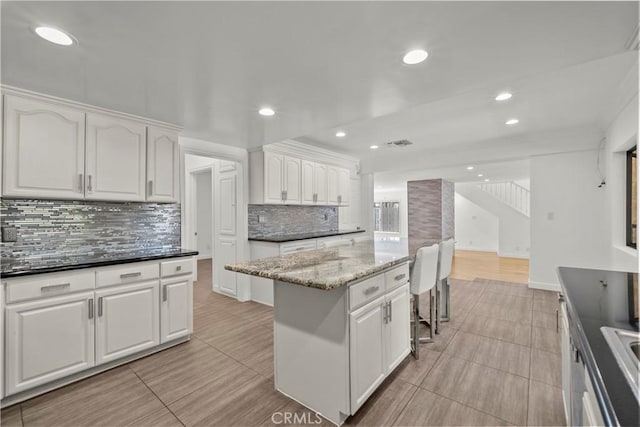 4919 Dunsmore Ave, La Crescenta, CA 91214 - kitchen with white cabinetry, tasteful backsplash, recessed lighting, dark stone countertops, and a center island