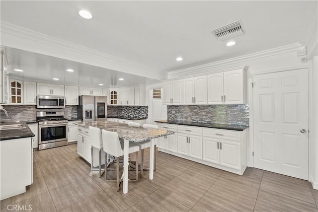 4919 Dunsmore Ave, La Crescenta, CA 91214 - kitchen featuring appliances with stainless steel finishes, decorative backsplash, white cabinetry, a kitchen bar, and glass insert cabinets