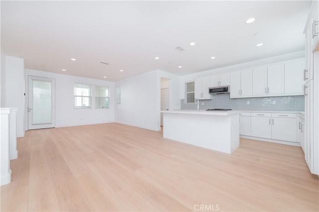 9570 Bluewater Pl, Rancho Cucamonga, CA 91730 - kitchen featuring light wood-type flooring, stainless steel microwave, white cabinets, tasteful backsplash, and recessed lighting