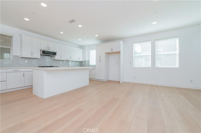 9570 Bluewater Pl, Rancho Cucamonga, CA 91730 - kitchen featuring light countertops, decorative backsplash, white cabinetry, light wood-style floors, and recessed lighting