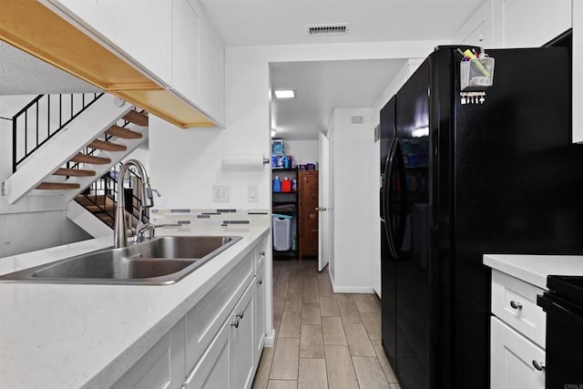 11935 Royal Rd Unit E, El Cajon, CA 92021 - kitchen with black refrigerator with ice dispenser, light countertops, and white cabinetry