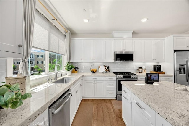 18361 Iris Ln, Yorba Linda, CA 92886 - kitchen featuring stainless steel appliances, white cabinetry, light wood-type flooring, backsplash, and light stone countertops