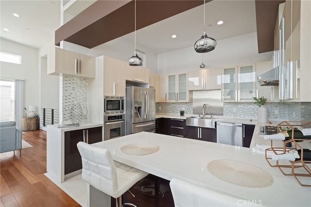 2623 Carnegie Ln, Redondo Beach, CA 90278 - kitchen featuring stainless steel appliances, light countertops, light wood-style floors, a peninsula, and backsplash