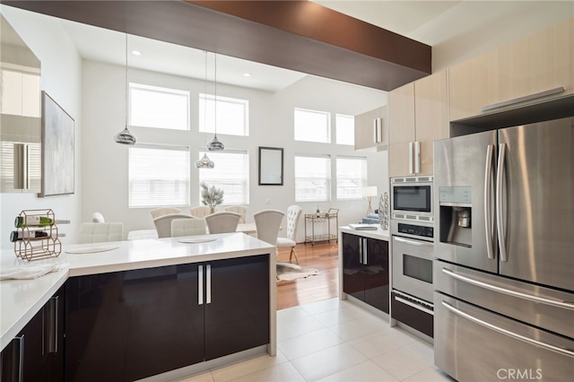2623 Carnegie Ln, Redondo Beach, CA 90278 - kitchen featuring stainless steel appliances, modern cabinets, light countertops, hanging light fixtures, and a towering ceiling