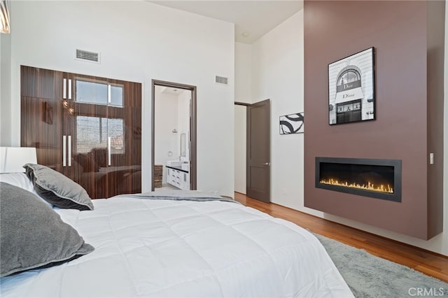 2623 Carnegie Ln, Redondo Beach, CA 90278 - bedroom featuring a towering ceiling, a glass covered fireplace, wood finished floors, and ensuite bathroom