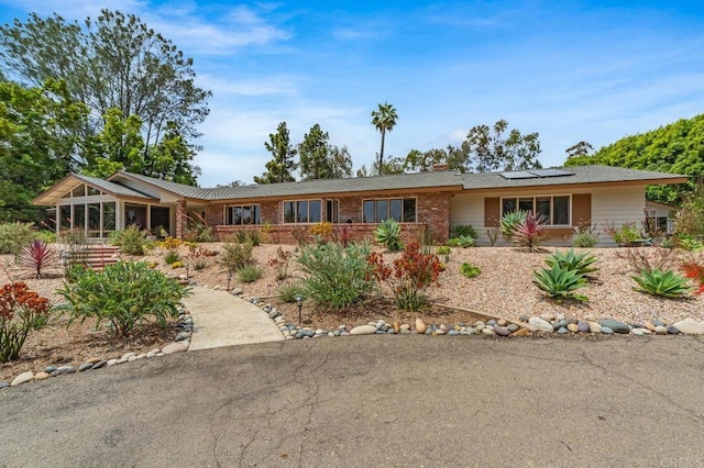 4678 Sun Vly, Del Mar, CA 92014 - ranch-style house with roof mounted solar panels, brick siding, a chimney, and a sunroom