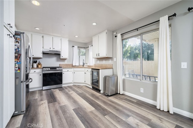 11718 Lucena Ave, Fontana, CA 92337 - kitchen featuring appliances with stainless steel finishes, wine cooler, under cabinet range hood, wood finished floors, and white cabinetry