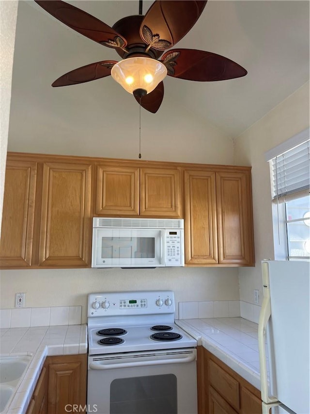 20301 Bluffside Cir Unit D406, Huntington Beach, CA 92646 - kitchen featuring white appliances, tile counters, vaulted ceiling, brown cabinets, and a ceiling fan
