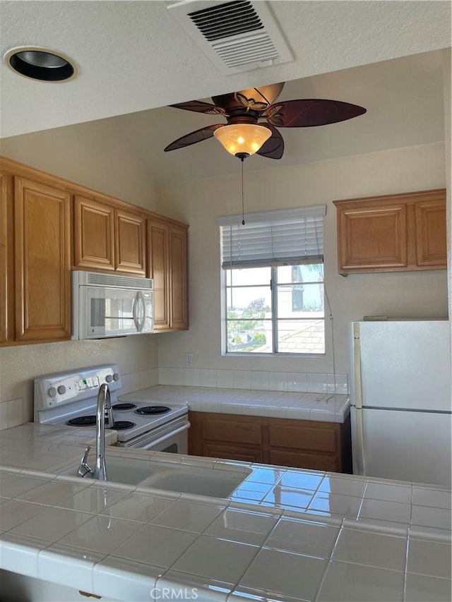 20301 Bluffside Cir Unit D406, Huntington Beach, CA 92646 - kitchen with white appliances, tile counters, a ceiling fan, brown cabinetry, and lofted ceiling