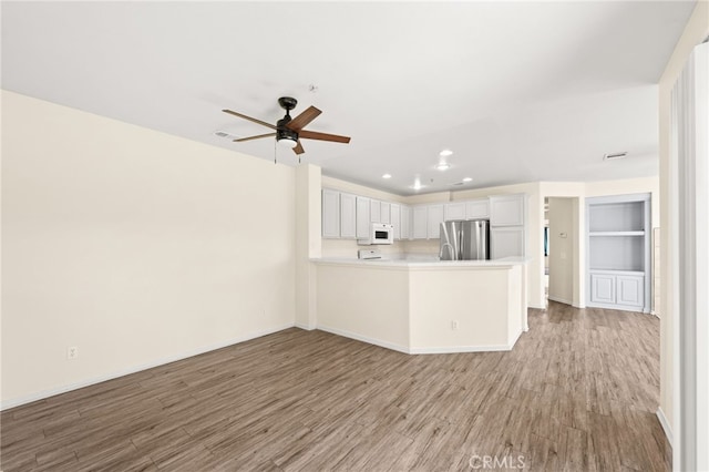 39719 Princeton Way Unit C, Murrieta, CA 92563 - kitchen featuring freestanding refrigerator, white microwave, light wood-style flooring, recessed lighting, and light countertops
