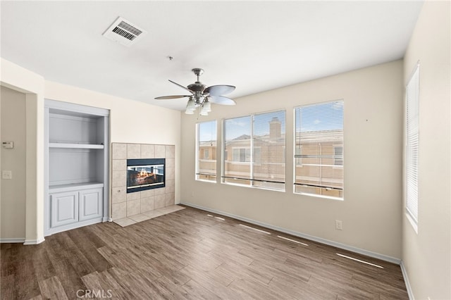 39719 Princeton Way Unit C, Murrieta, CA 92563 - unfurnished living room featuring wood finished floors, a fireplace, ceiling fan, and built in shelves