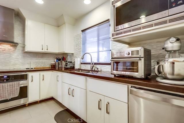 1313 Valley View Rd Unit 103, Glendale, CA 91202 - kitchen with appliances with stainless steel finishes, wall chimney range hood, dark countertops, backsplash, and white cabinets