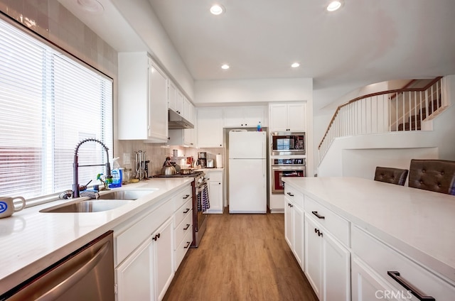 8550 Rolling Hills Dr, Corona, CA 92883 - kitchen featuring appliances with stainless steel finishes, light wood finished floors, under cabinet range hood, light countertops, and white cabinetry