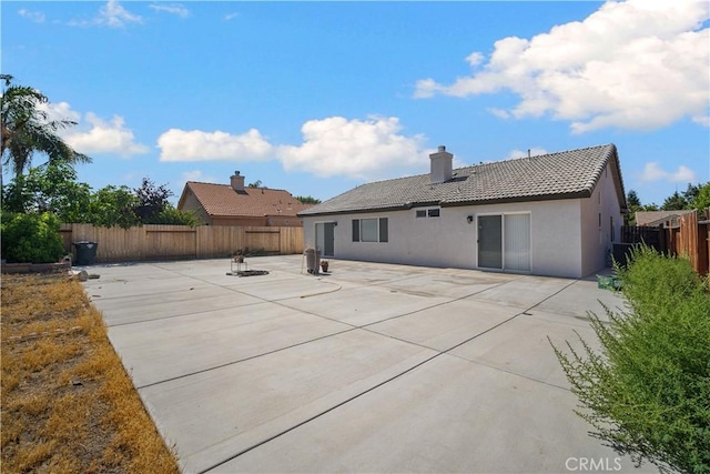 5224 Sierra Caves Ave, Bakersfield, CA 93313 - back of house with a tiled roof, a patio area, stucco siding, a fenced backyard, and a chimney