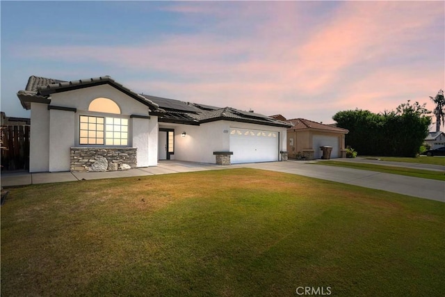 5224 Sierra Caves Ave, Bakersfield, CA 93313 - view of front of house with stone siding, roof mounted solar panels, driveway, a front lawn, and stucco siding