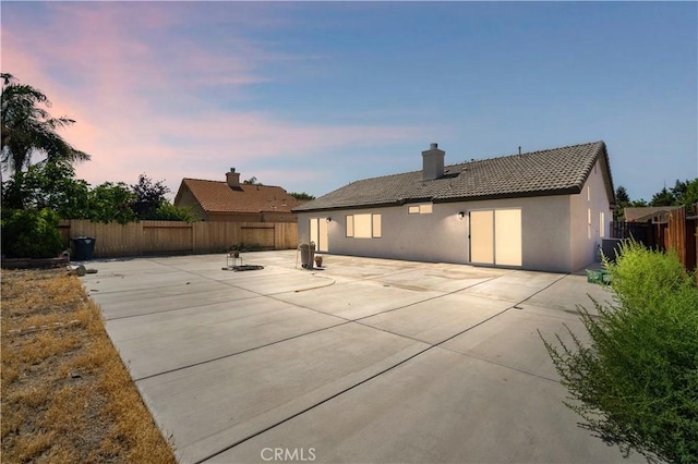 5224 Sierra Caves Ave, Bakersfield, CA 93313 - back of property with a tiled roof, stucco siding, a patio, a fenced backyard, and a chimney