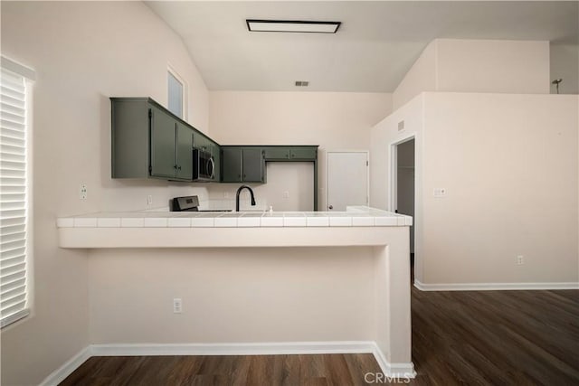 5224 Sierra Caves Ave, Bakersfield, CA 93313 - kitchen with stainless steel microwave, a peninsula, dark wood finished floors, and tile countertops