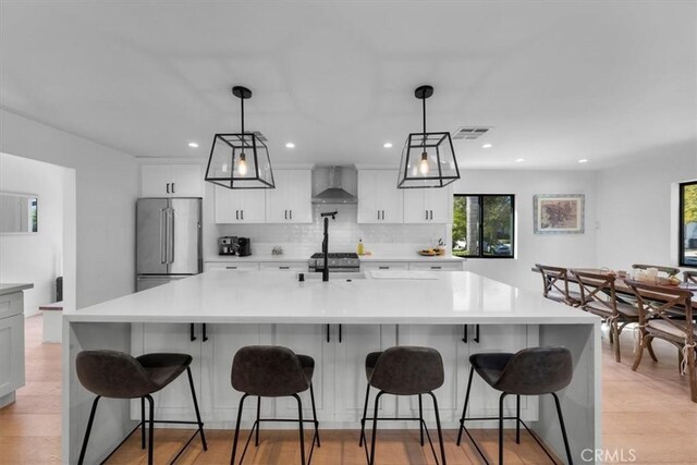 1834 Stearns Dr, Los Angeles, CA 90035 - kitchen with wall chimney exhaust hood, stainless steel appliances, backsplash, white cabinetry, and light countertops