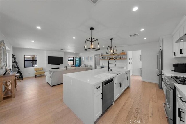 1834 Stearns Dr, Los Angeles, CA 90035 - kitchen with premium appliances, white cabinets, recessed lighting, light wood-type flooring, and a center island with sink