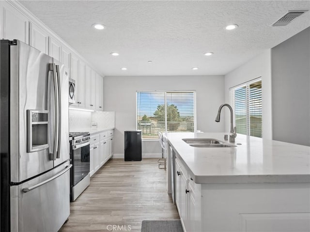 15679 Tuscola Rd, Apple Valley, CA 92307 - kitchen with appliances with stainless steel finishes, recessed lighting, plenty of natural light, light wood-style flooring, and white cabinets