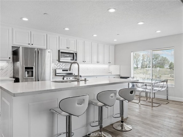 15679 Tuscola Rd, Apple Valley, CA 92307 - kitchen featuring stainless steel appliances, white cabinetry, tasteful backsplash, recessed lighting, and light wood finished floors